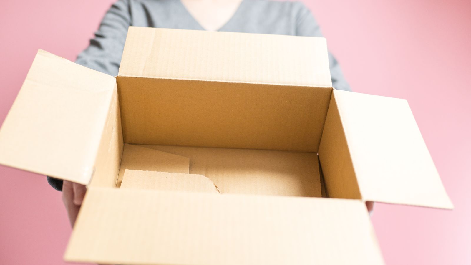 A shot of a person holding an empty box in a well lit area