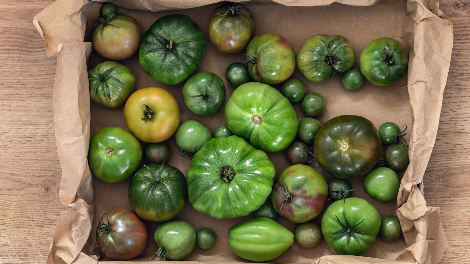 An overhead shot of several green colored unripe fruits in a box