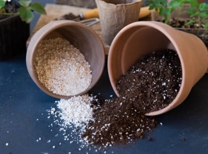 A close-up shot of several tipped over pots with spilled ground perlite and vermiculite, mixed with soil