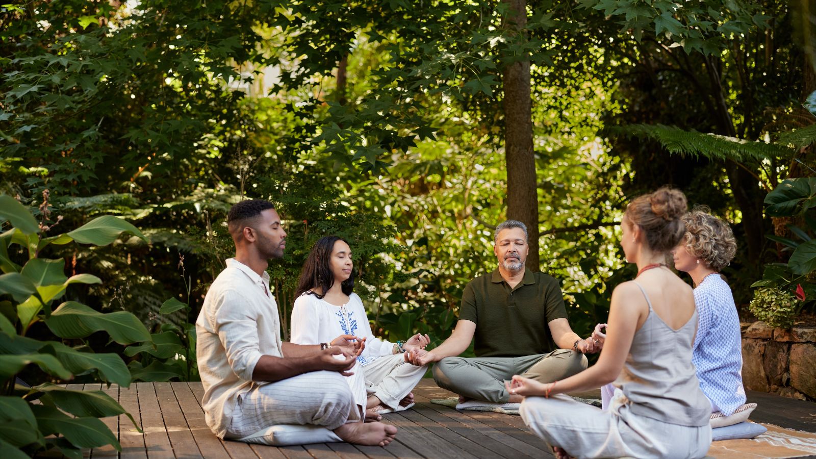 A close-up shot of a small group of diverse people, meditating in a tree forest area outdoors