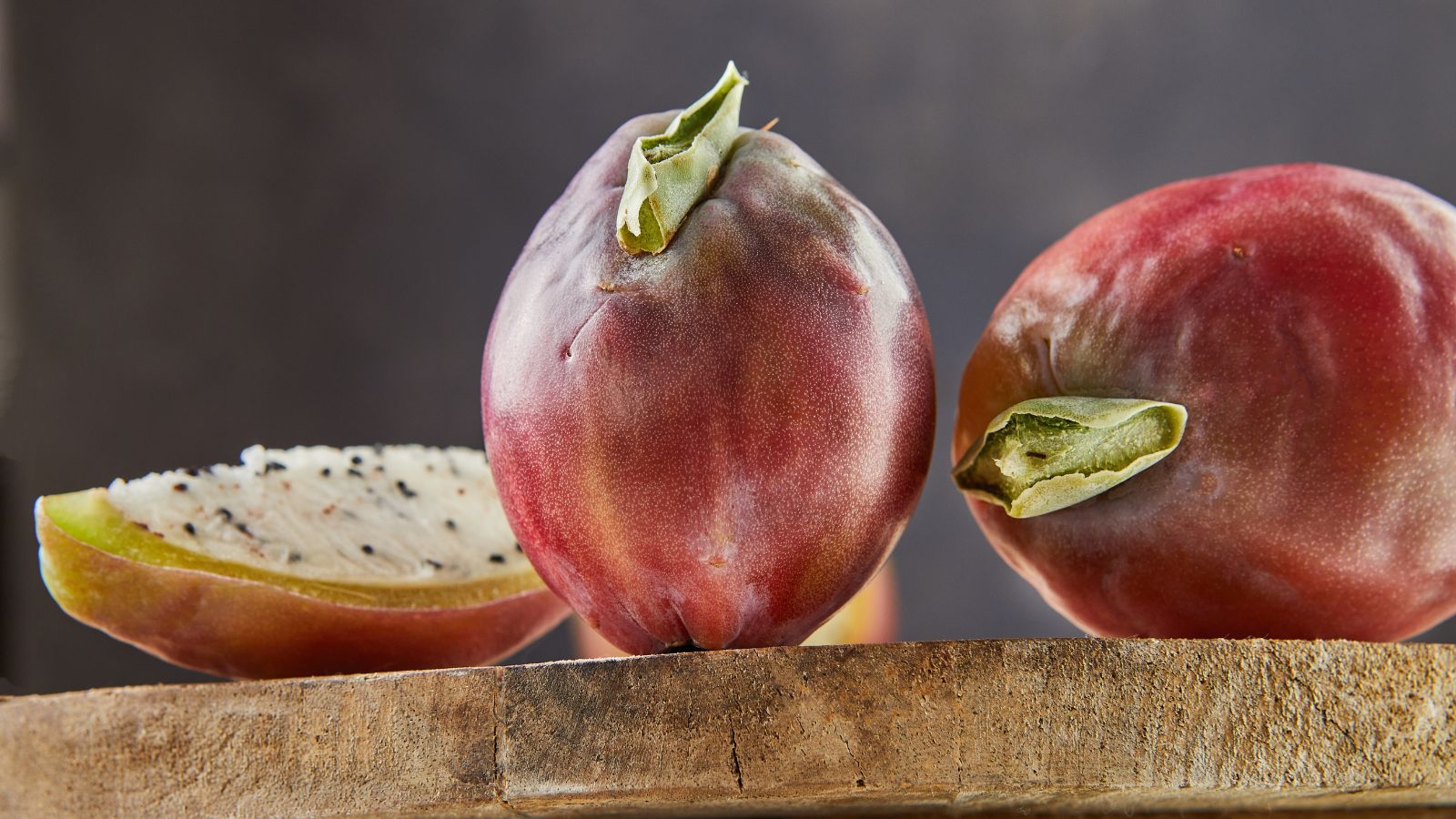 Cereus peruvianus fruits on a wooden surface, appearing round and smooth with a dark background