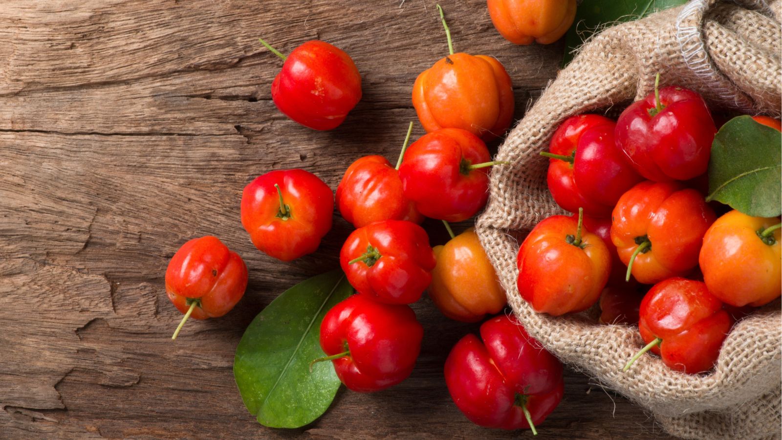 An overhead shot of freshly harvested fruits on a sack, all placed on top of a wooden surface