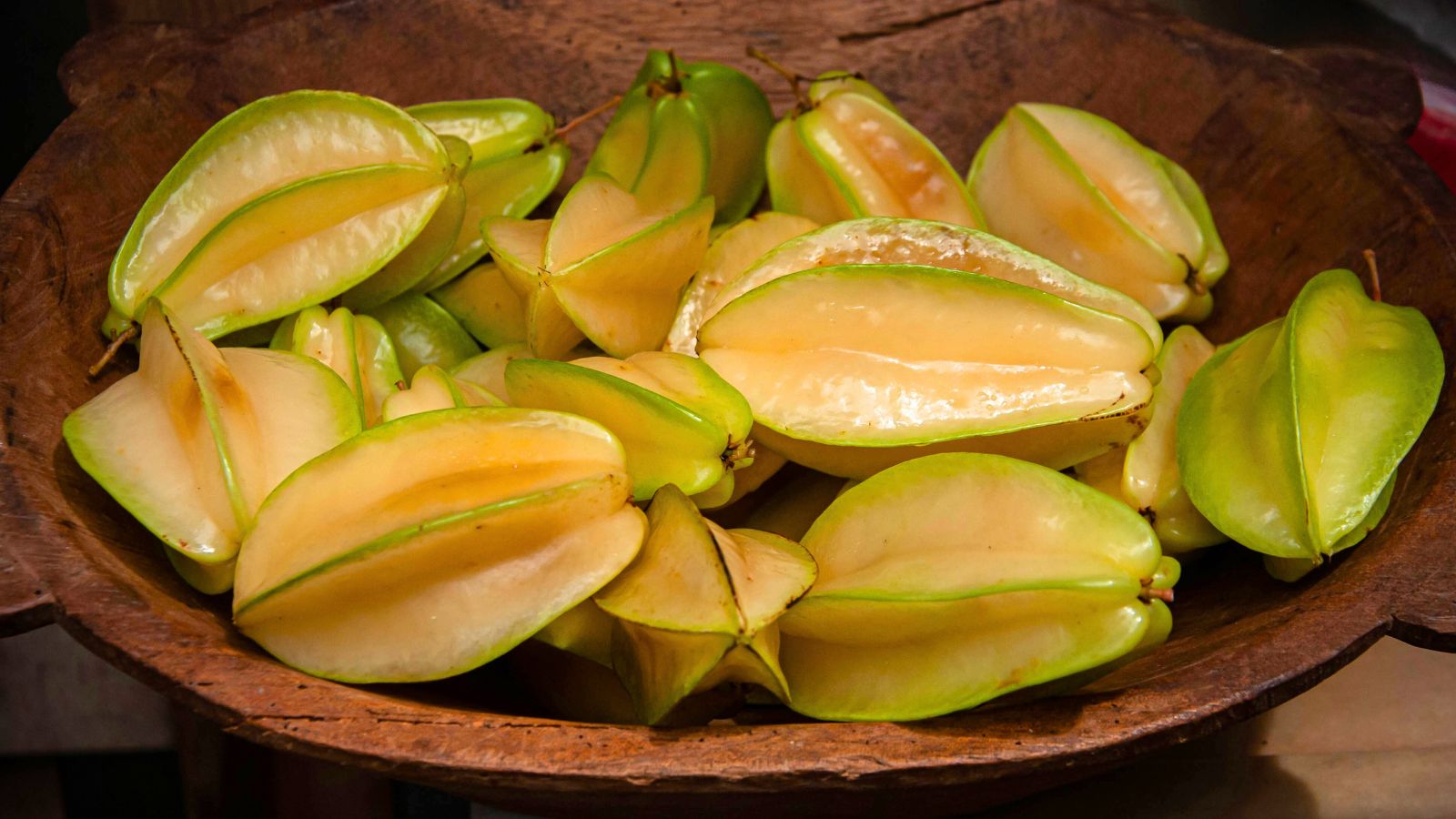 A shot of freshly harvested fruits that is piled up on top of each other and are placed on a wooden tray