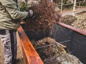 A close-up shot of a person in the process of filling up a newly built planter, showcasing the hugelkultur raised bed