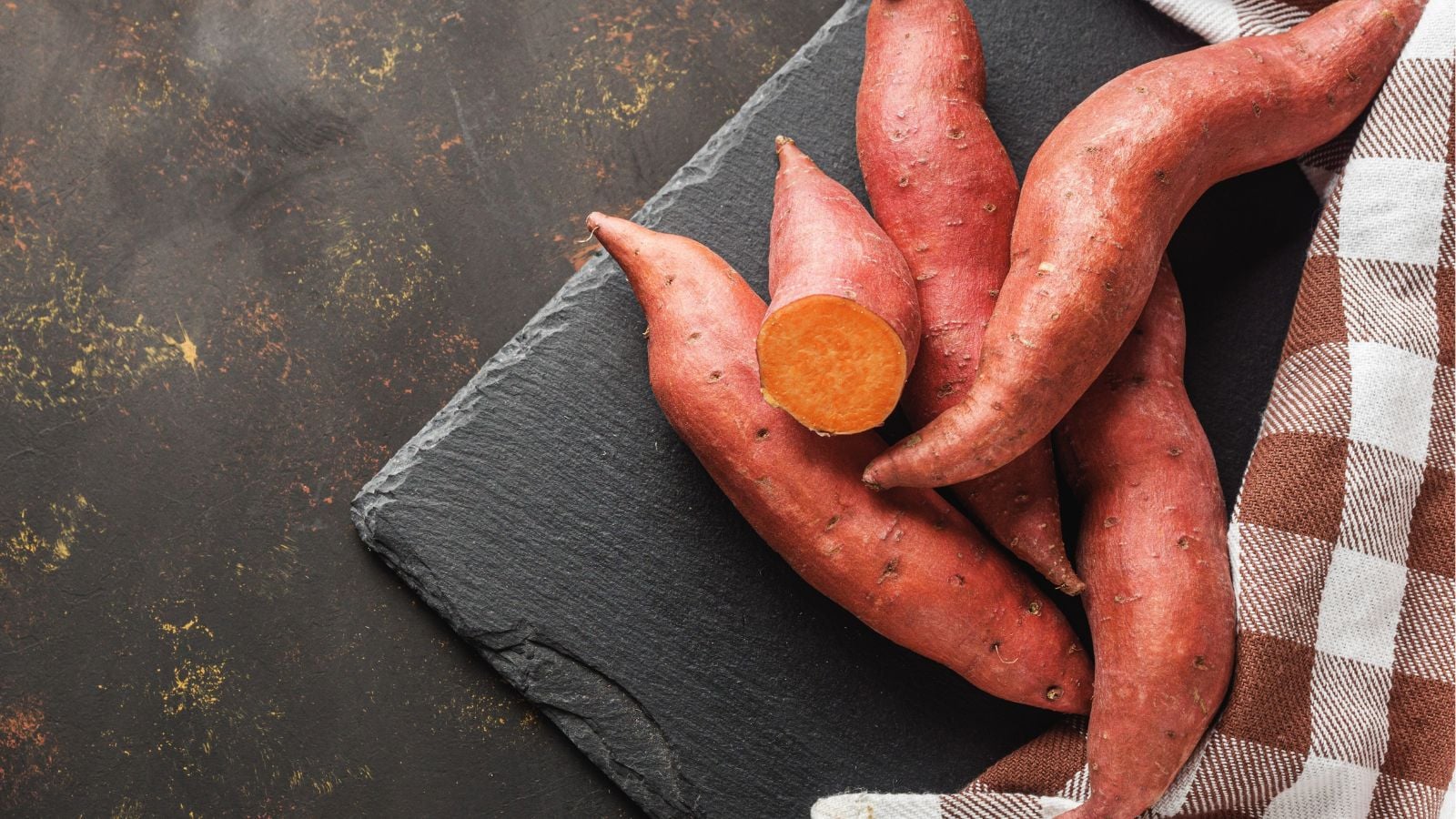An overhead and close-up shot of a small pile of Burgundy variety of crops, showcasing their red skin and bright orange flesh, all placed in a well lit area