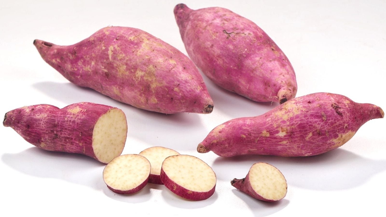 A close-up and isolated shot of several reddish-purple colored crops called Murasaki, featuring a pale white flesh