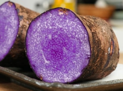 A close-up shot of a sliced, raw and uncooked root crop, placed on a small plate, called the dioscorea alata