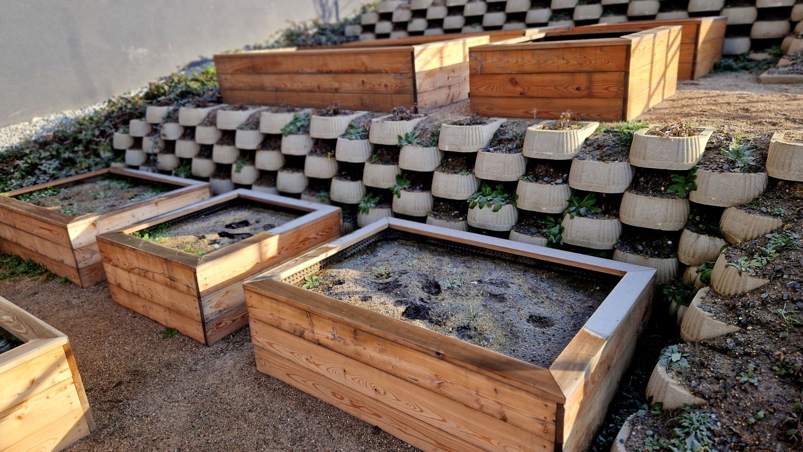 A shot of several containers placed near a landscaped, sloped, garden area outdoors