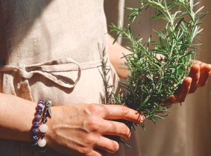 A shot of a peron holding an herb that showcases how to harvest rosemary