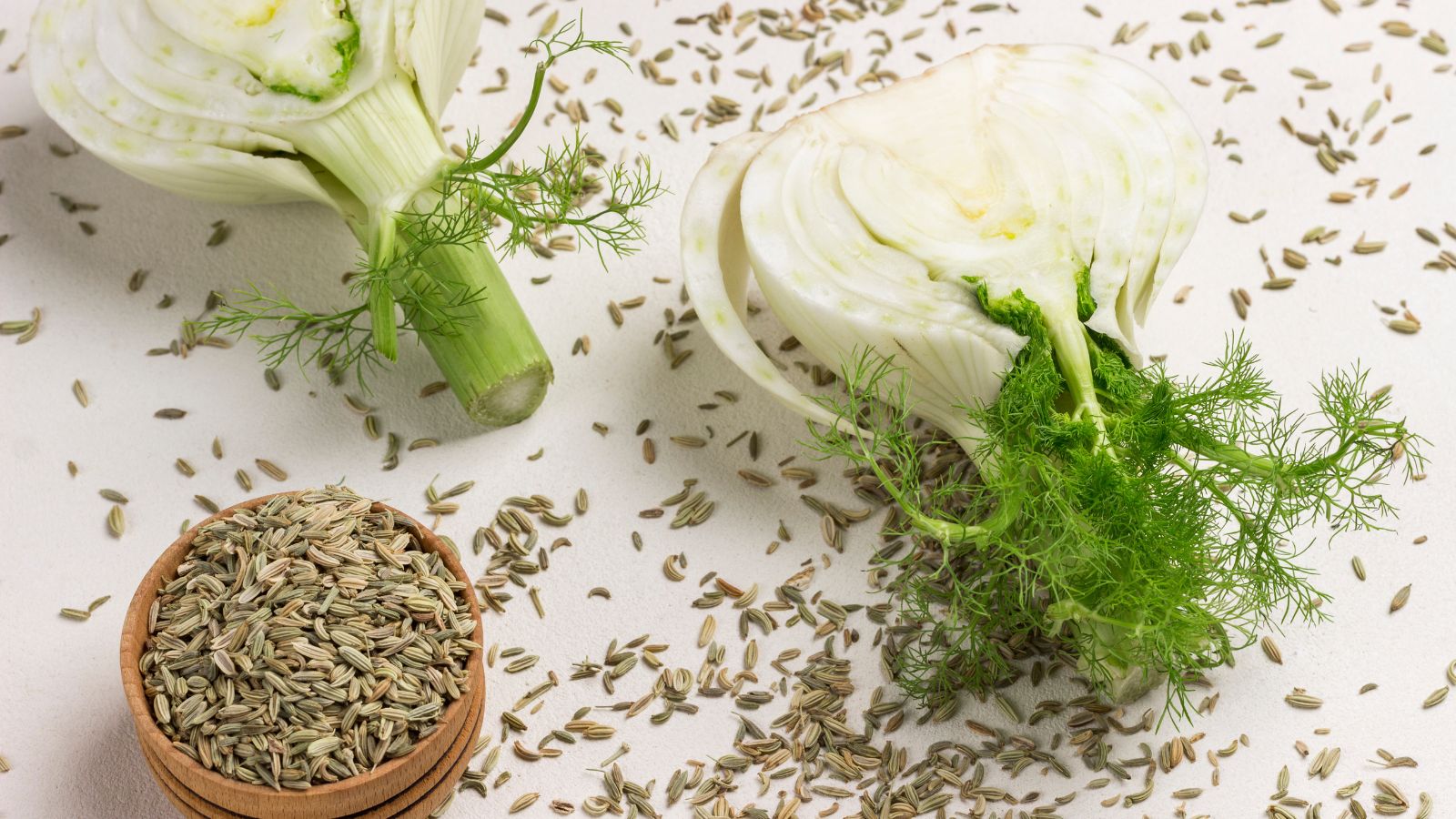 An overhead shot of seeds and sliced bulb of a crop