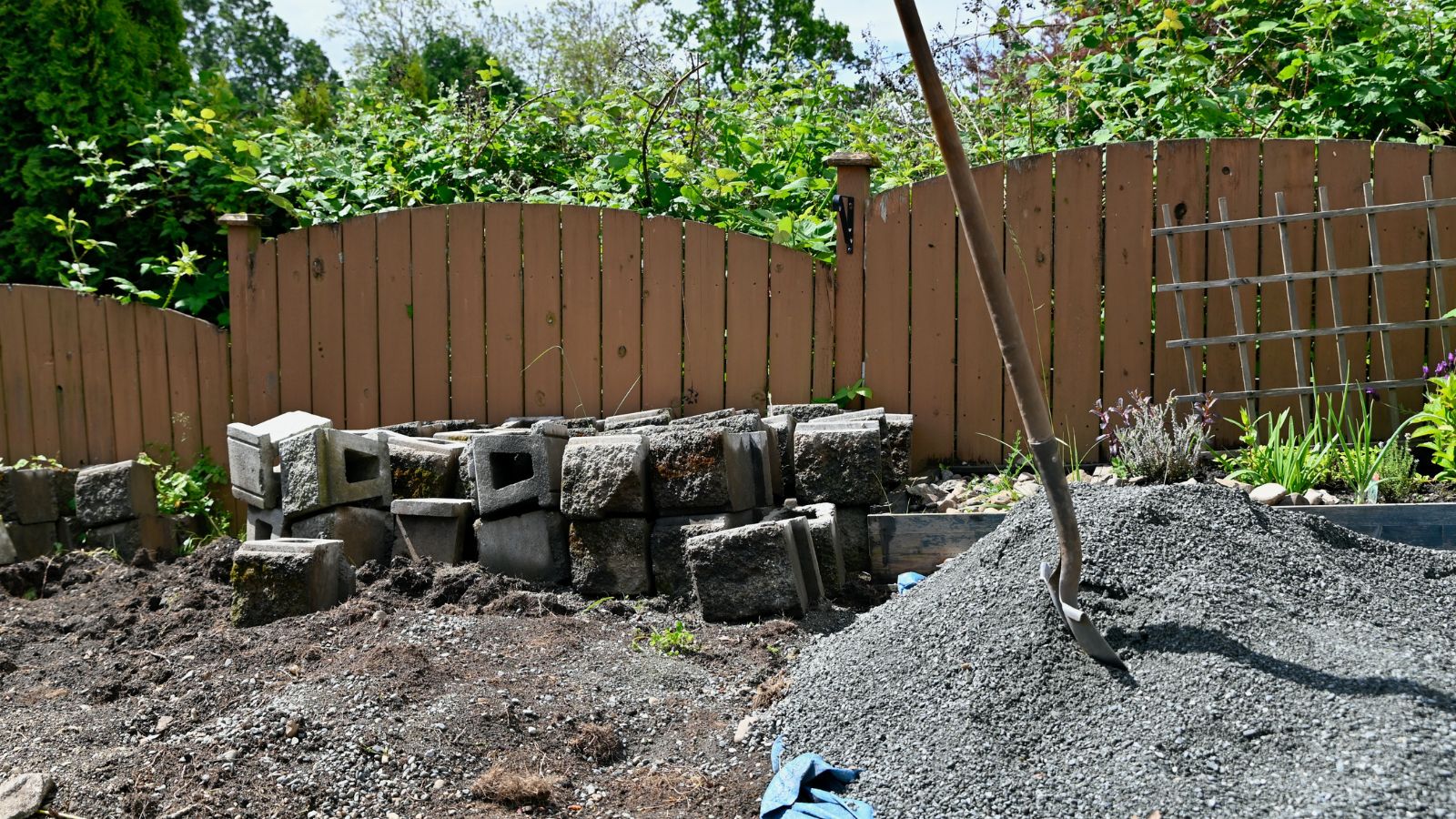 A shot of an area in the process of being reinforced with a pile of gravel and sand in a well lit garden area outdoors