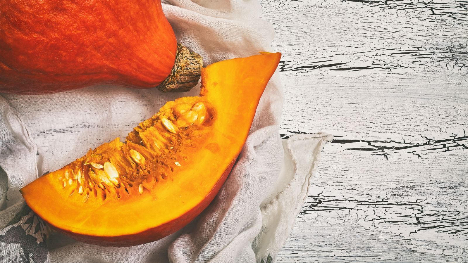 A slice of an orange and round crop with orange flesh and white seeds