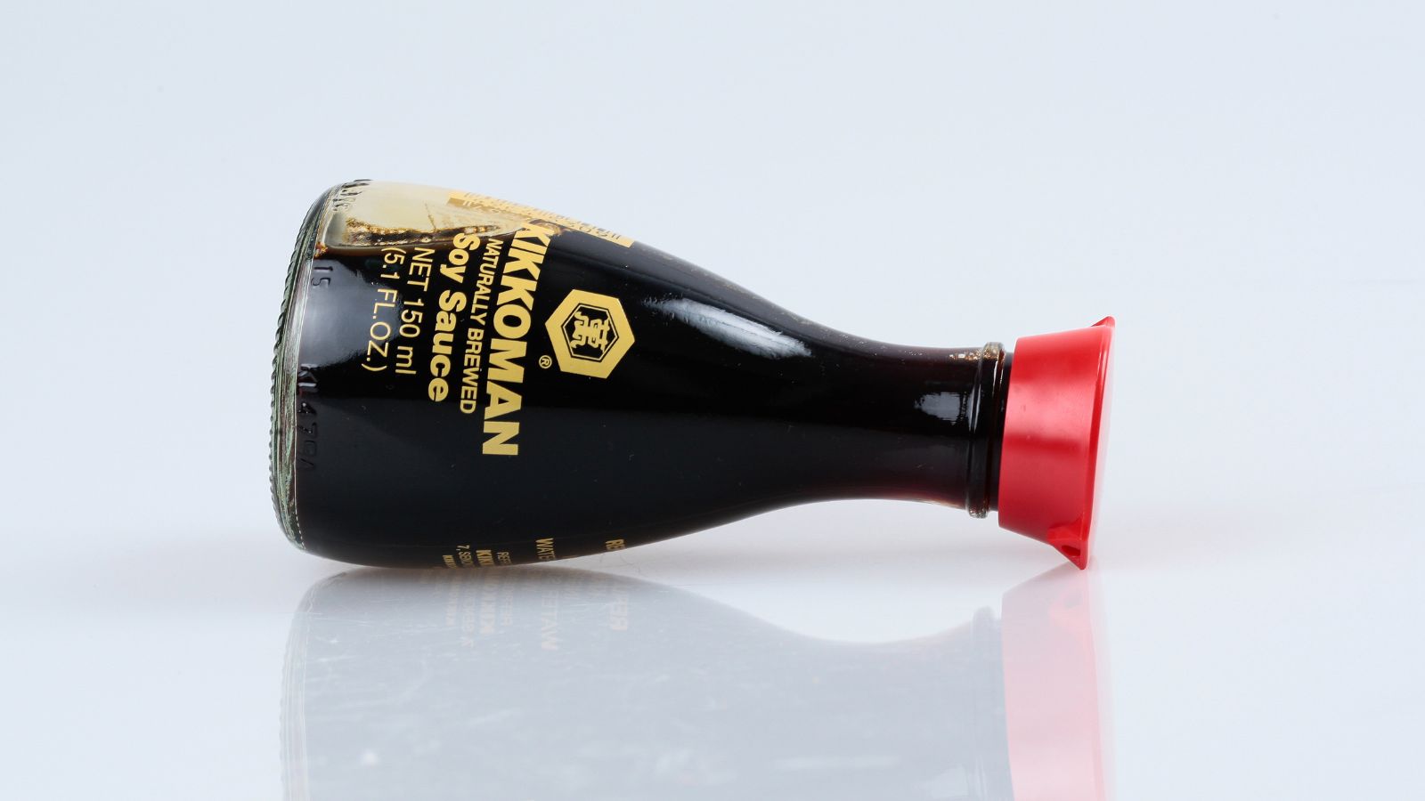 A close-up and isolated shot of a bottle of soy sauce, placed on a white surface in doors