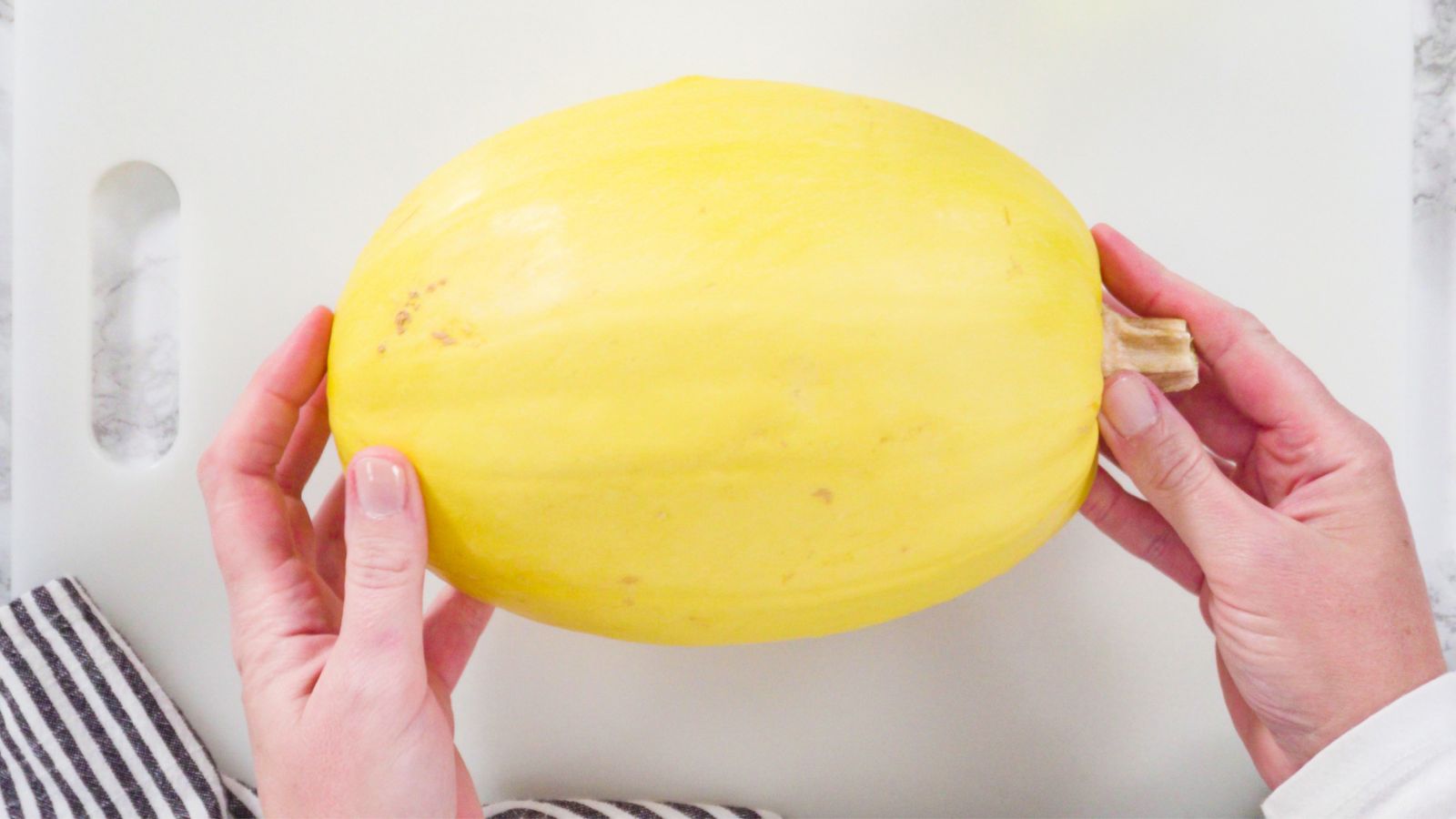 A shot of a person in the process of preparing a yellow gourd in a well lit area indoors