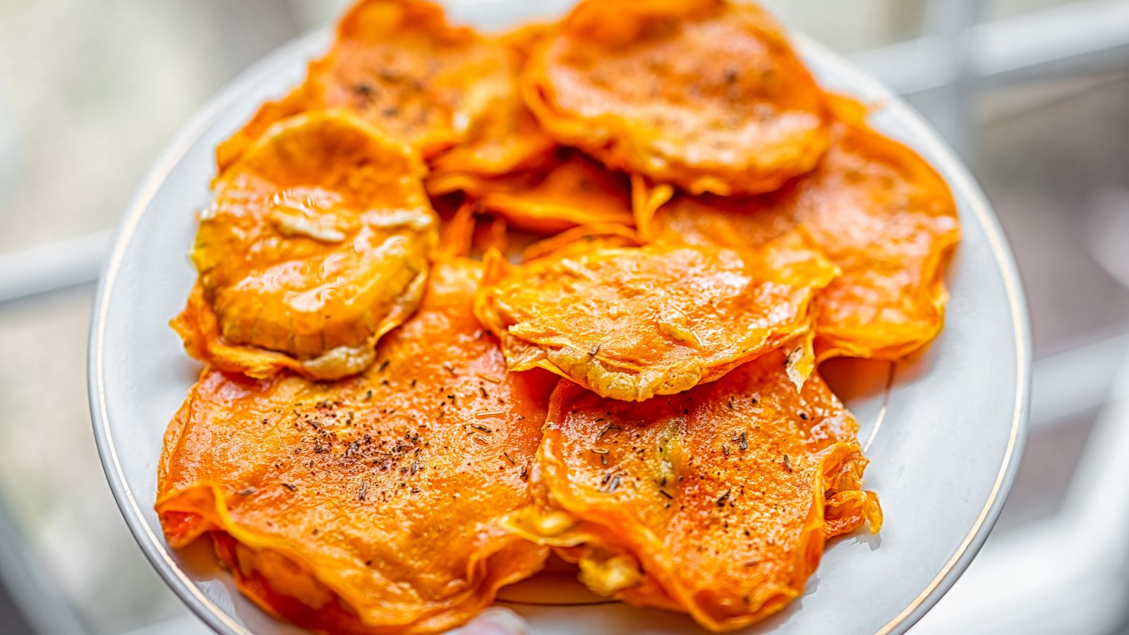 A shot of a person holding a plate of dehydrated orange gourds