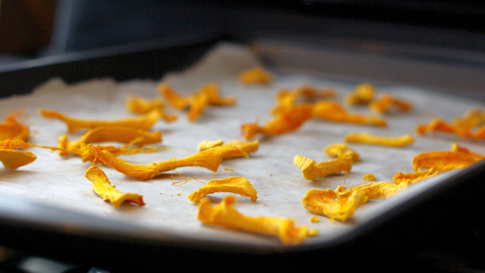A close-up shot of dried orange crops on a baking tray indoors
