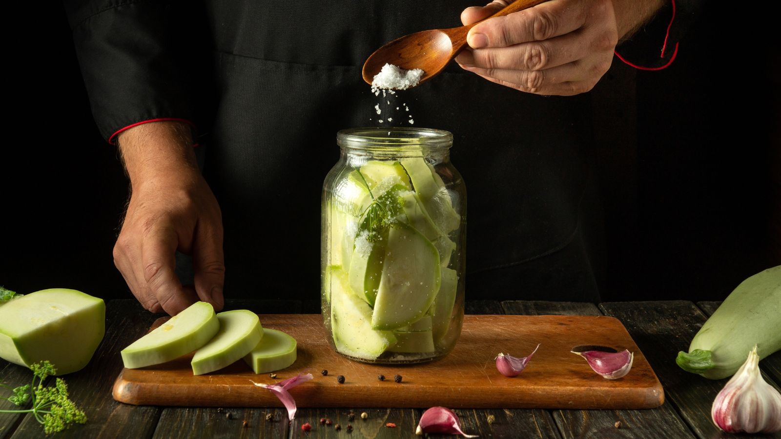 A person in the process of pickling a gourd in a jar in an area indoors