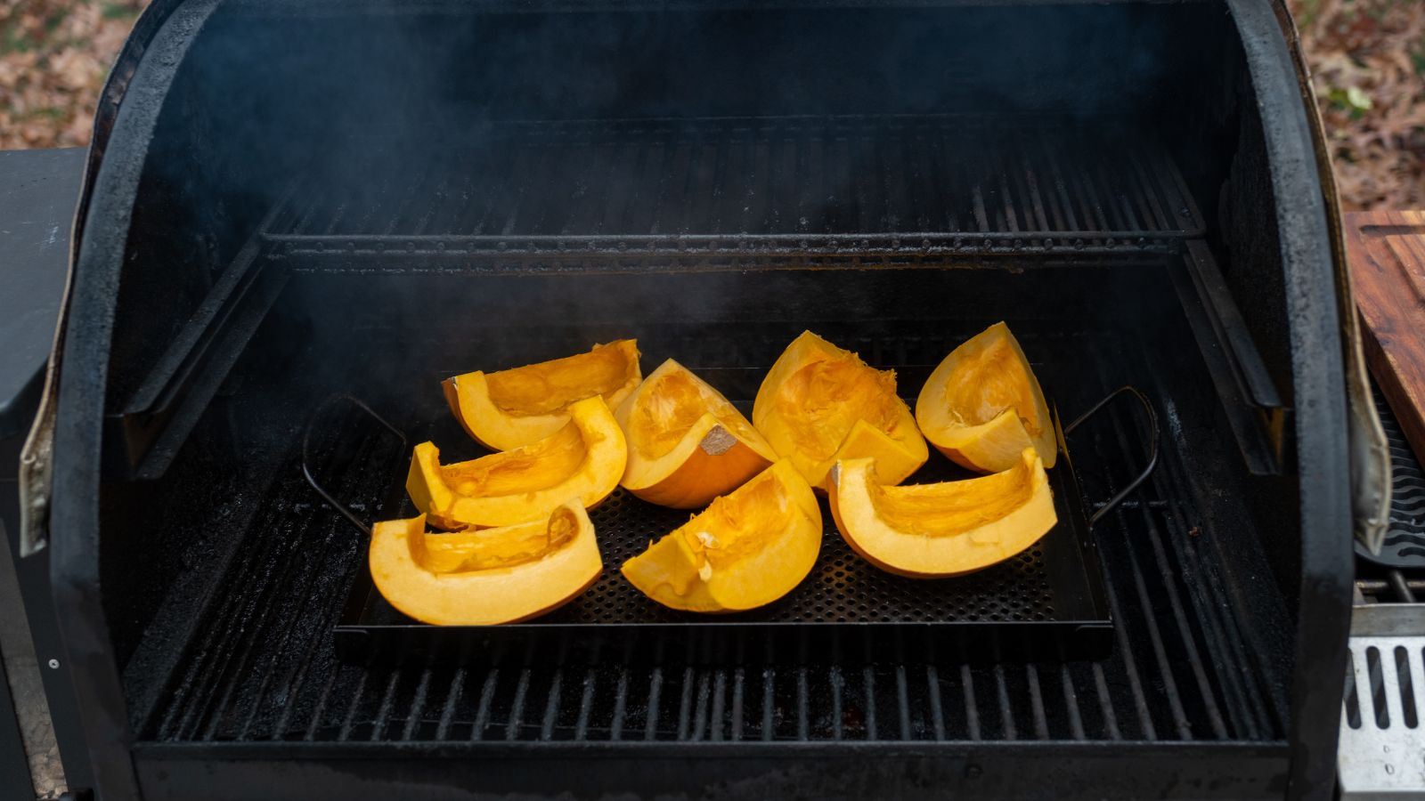 A shot of orange crops being smoked in a smoker in a well lit area outdoors