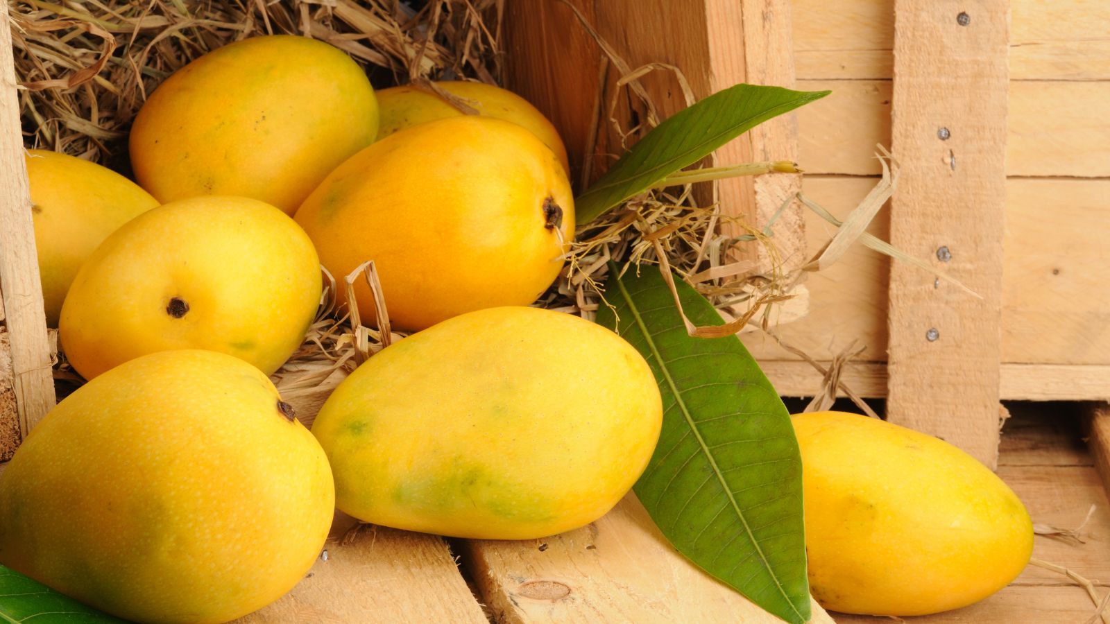 A shot of several piled ripe fruits in a wooden container
