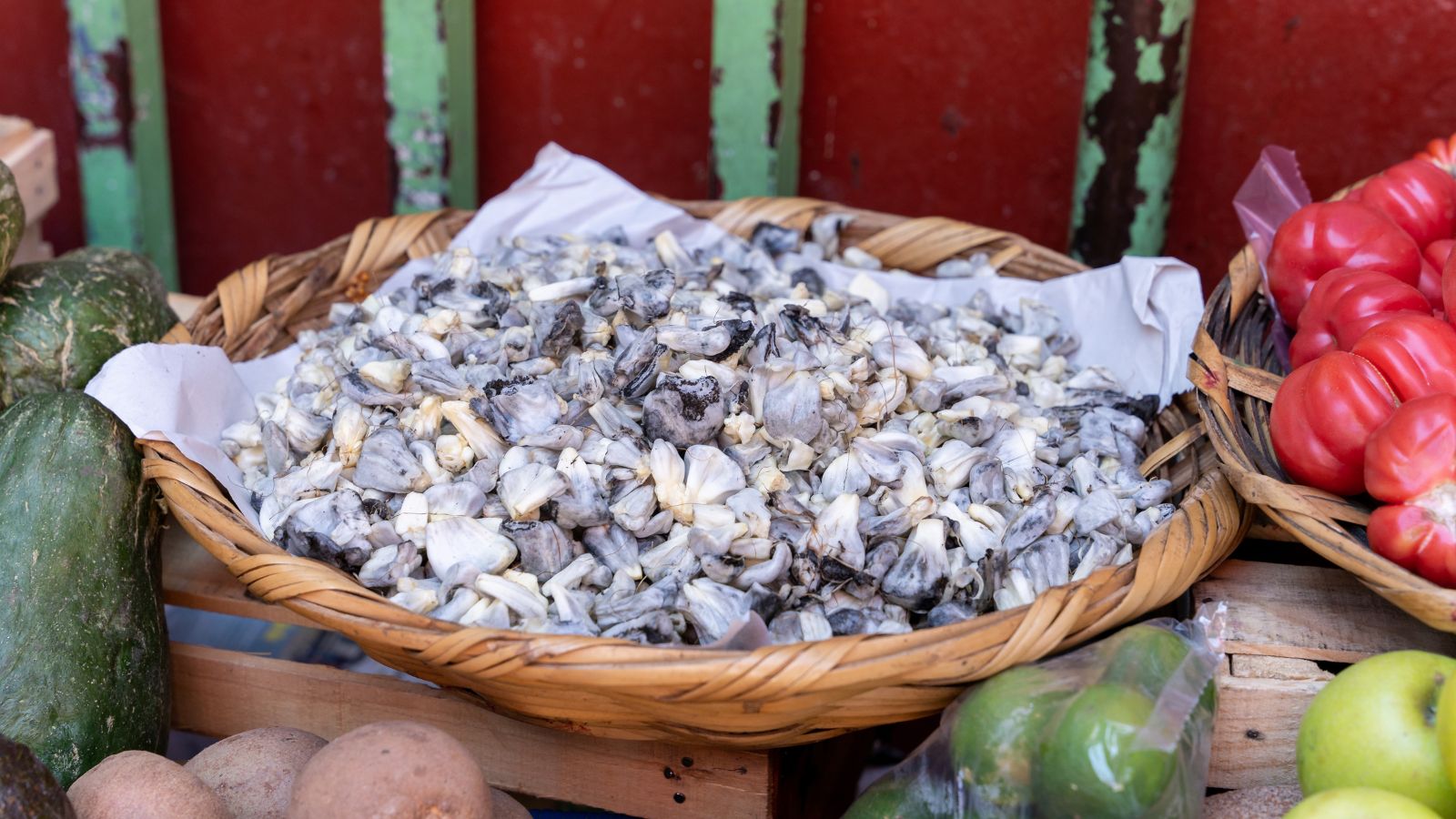 The result of a Zea mays fungal infection appearing to be clumps of matter placed in a woven basket on a market stand beside various produce